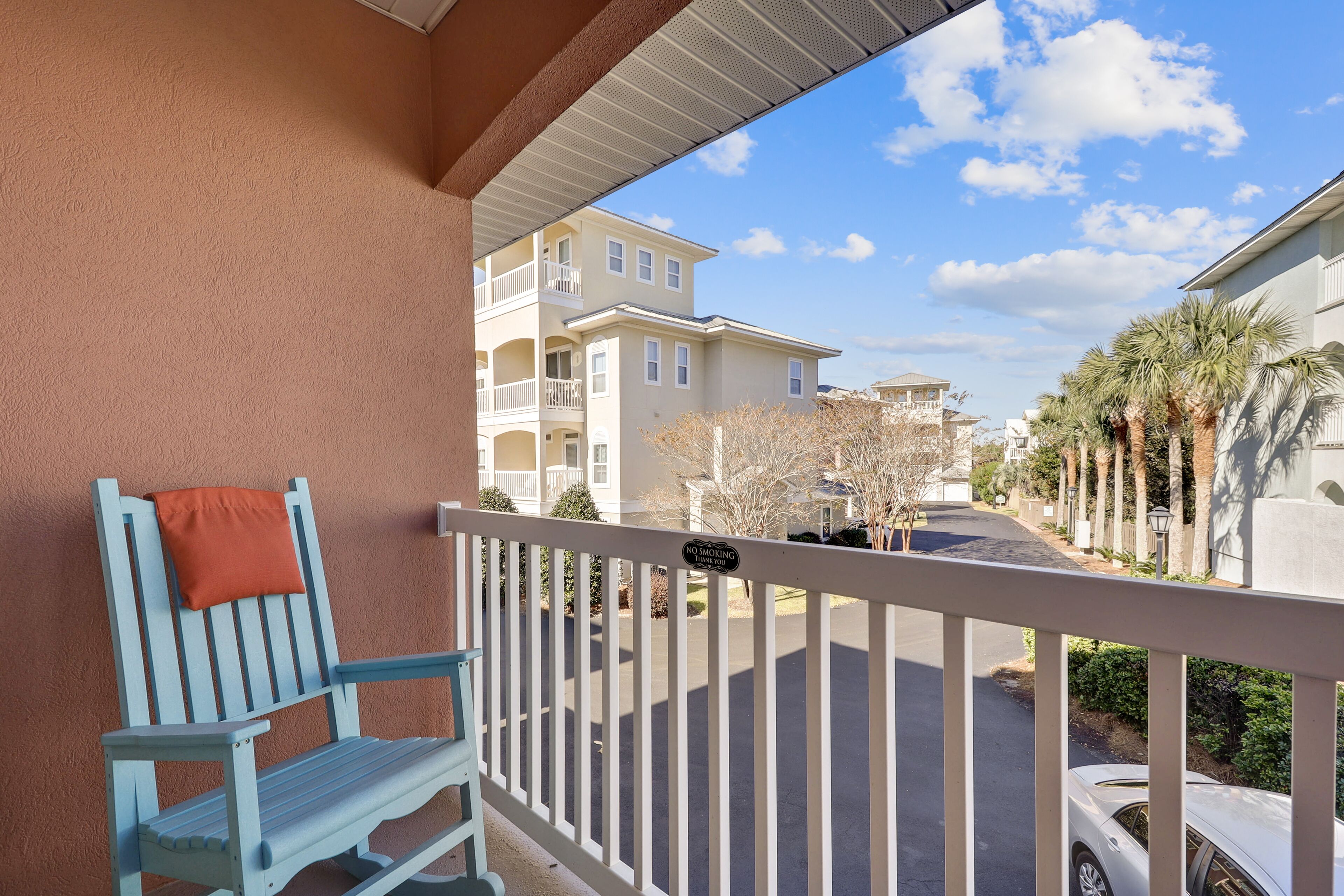 A balcony with a white railing, a blue chair, and a 'No Smoking' sign.