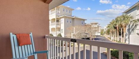A balcony with a white railing, a blue chair, and a 'No Smoking' sign.