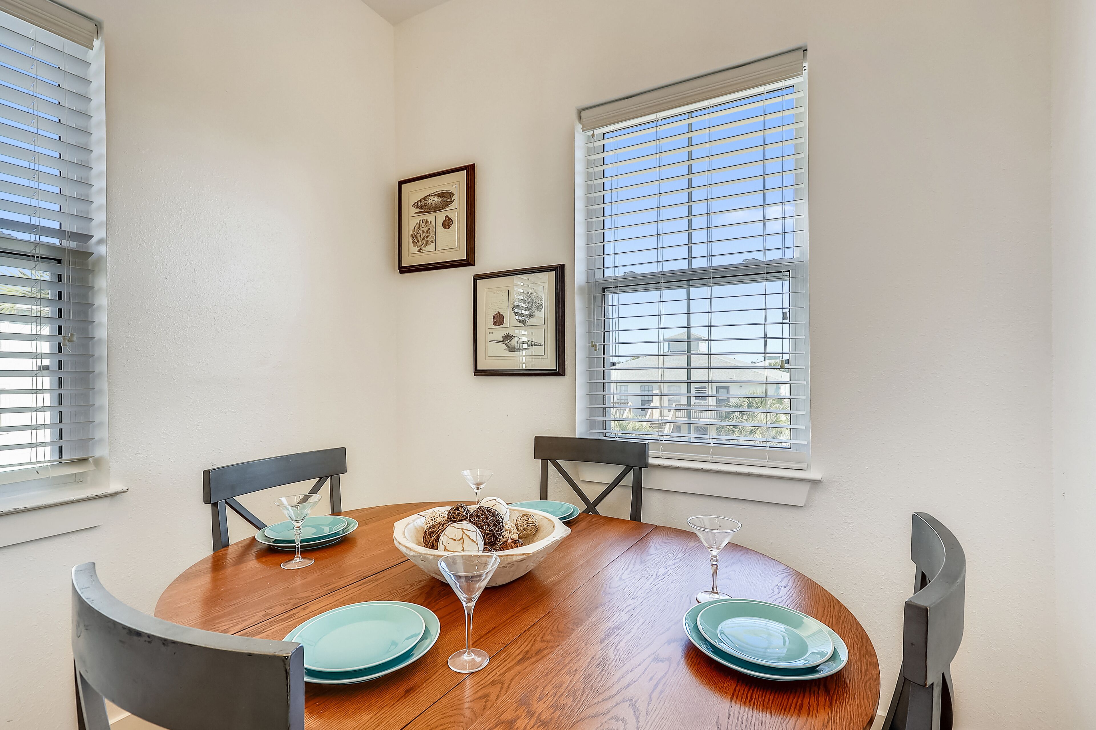 A dining area with a round wooden table, teal plates, and a bowl of snacks.