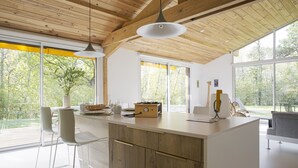 Une cuisine moderne avec un plafond en bois, de grandes fenêtres et un îlot central.