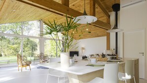 Une cuisine moderne dotée d’un grand îlot central, de chaises blanches et d’un luminaire suspendu.
