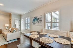 Relax in this inviting living room with a sofa, dining table, and artwork.
