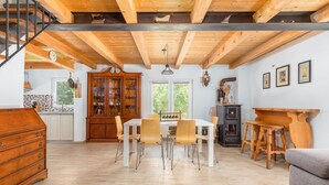 A spacious kitchen with wooden cabinets, a dining area with a white table and chairs, and a staircase with a metal railing. - Pet friendly home in Krnicari (Krnicari)