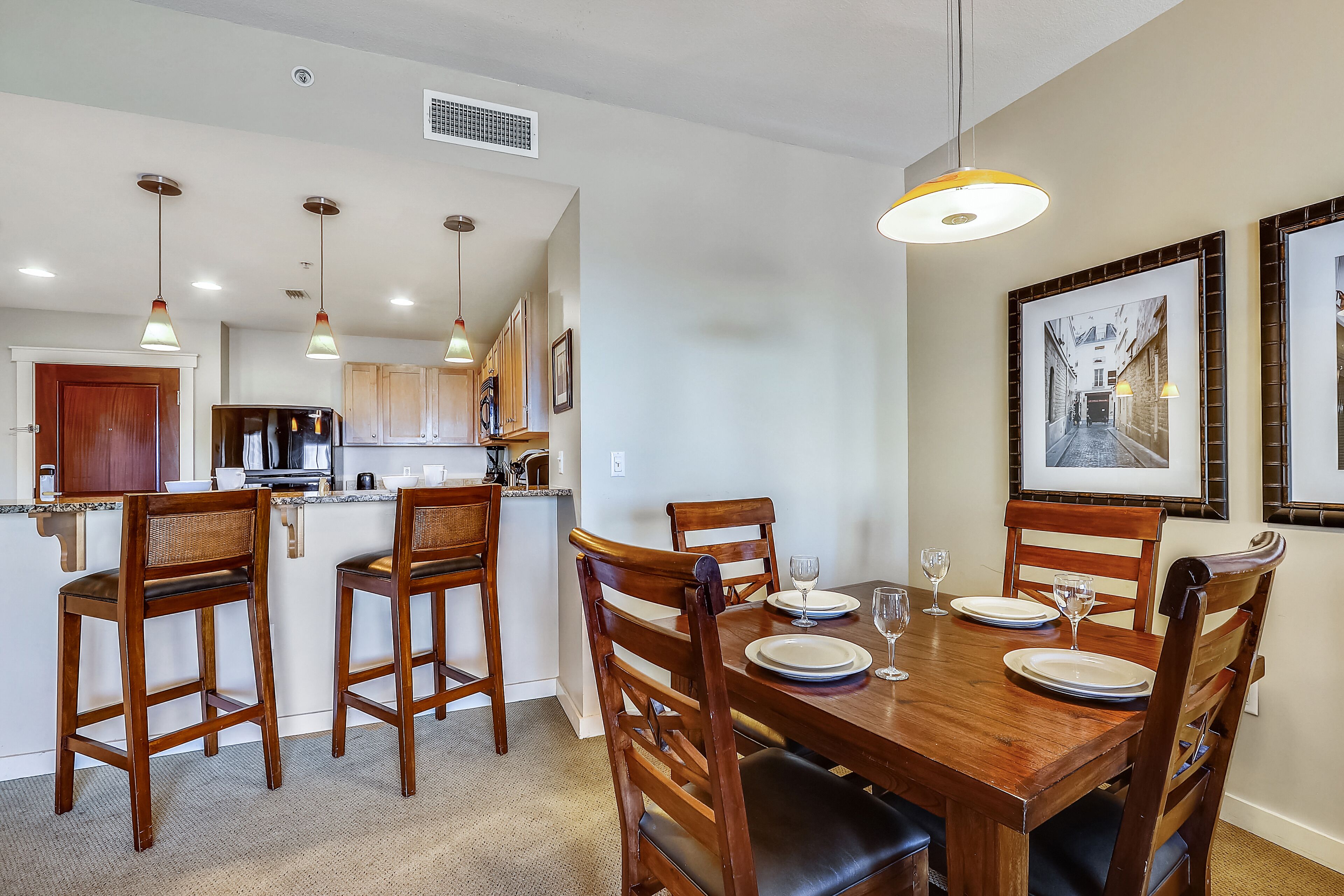 Comedor con una mesa de madera dispuesta para cuatro personas, rodeada de sillas de madera.