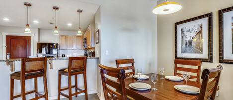 Comedor con una mesa de madera dispuesta para cuatro personas, rodeada de sillas de madera.
