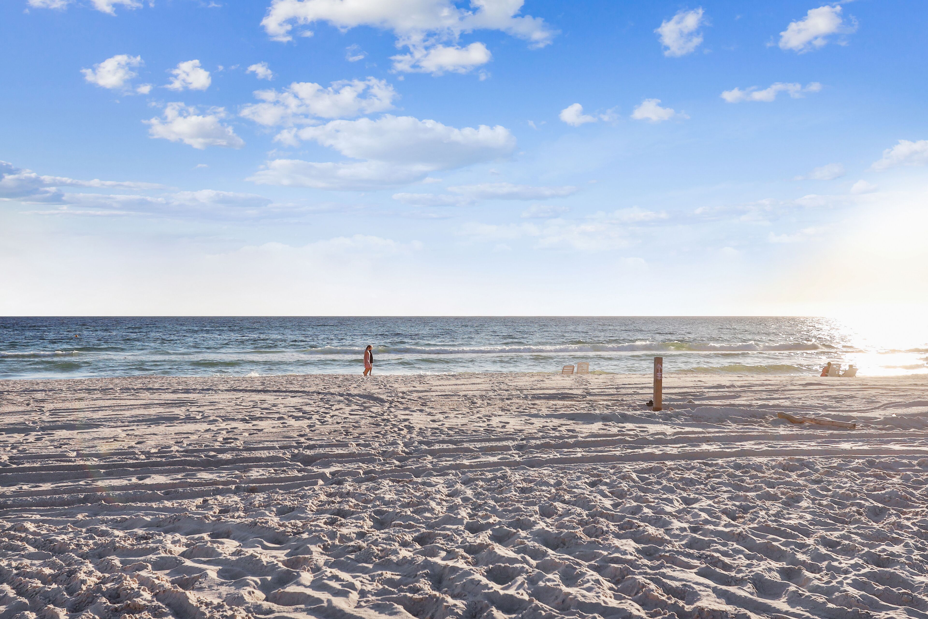A beach with sand, a few people, and the ocean.
