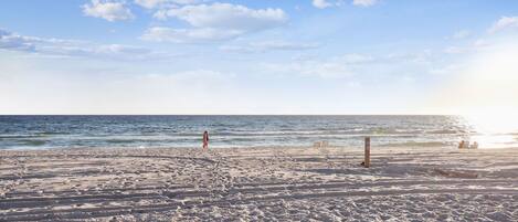 A beach with sand, a few people, and the ocean.