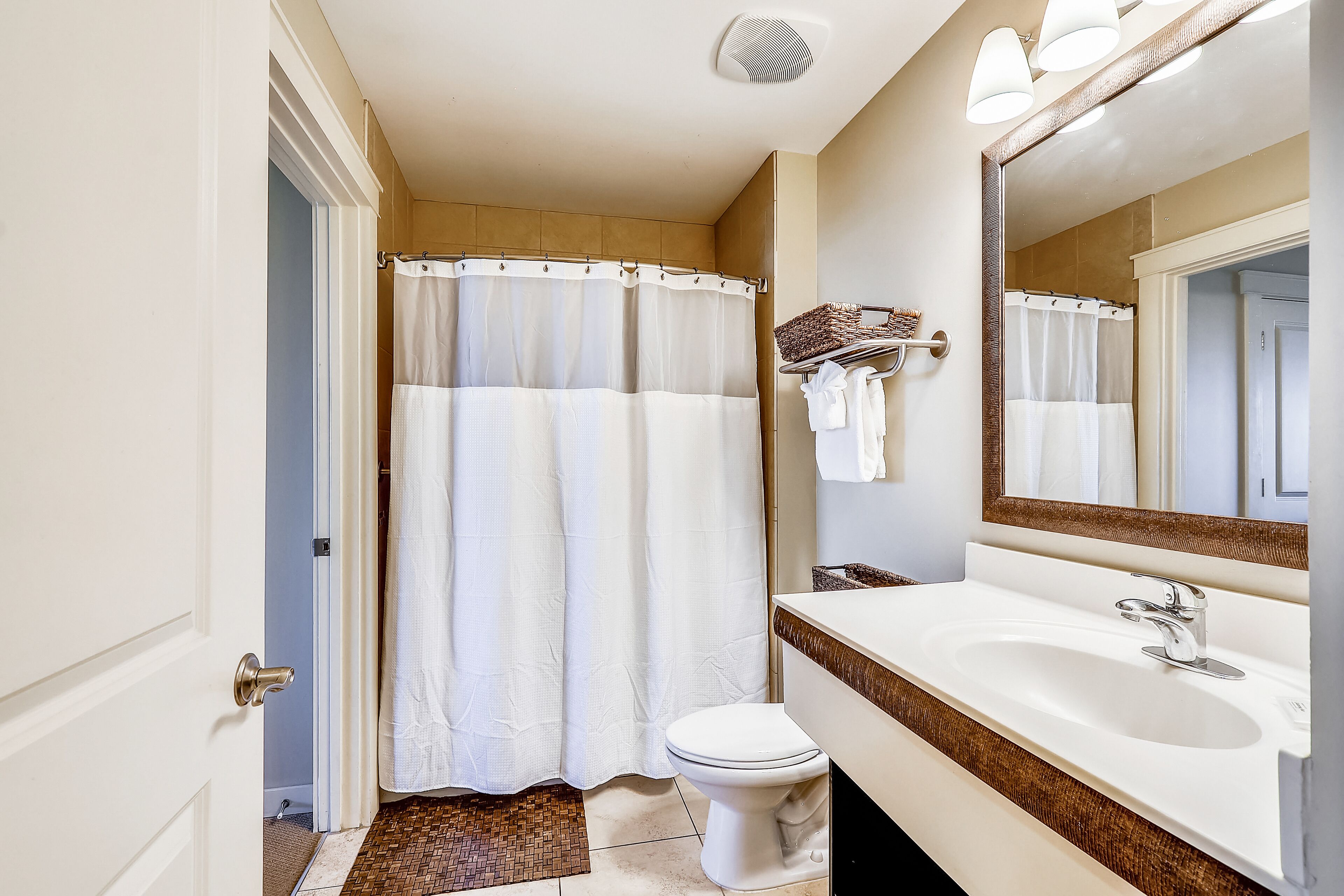 Un baño con lavamanos blanco, espejo y cortina de ducha.