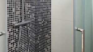 A shower with a glass door and a tiled wall. - Studio ideally located and quiet 15 eme arrondissement (Paris)