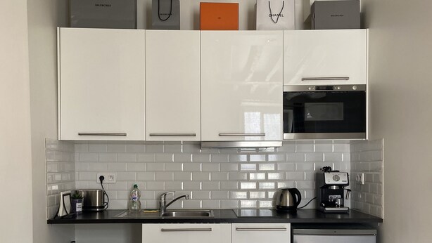 A compact kitchen with white cabinets, a black countertop, a built-in oven, and a small refrigerator. - Studio ideally located and quiet 15 eme arrondissement (Paris)