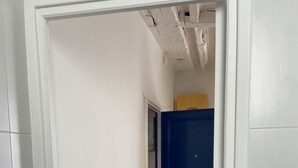 A narrow hallway with white walls and a wooden floor. A blue door is visible in the distance. - Studio ideally located and quiet 15 eme arrondissement (Paris)