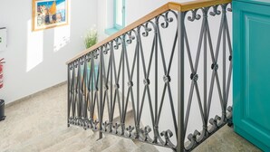 Een trap met een metalen leuning en een houten handrail, die leidt naar een deur in een blauwgroene kleur.