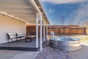Un patio couvert aménagé avec du mobilier d’extérieur, un jacuzzi et une clôture en bois en arrière-plan.