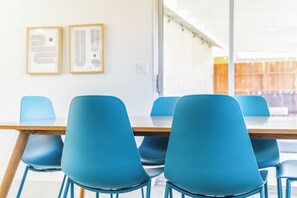 Ein Konferenzraum mit langem Tisch und blauen Stühlen, Bildern an der Wand und freundlicher Einrichtung.