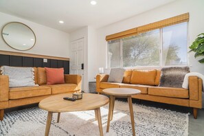 Ein modernes Wohnzimmer mit zwei Sofas, einem Couchtisch und einem großen Fenster.
