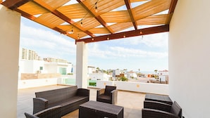 A covered outdoor seating area with wicker furniture and a view of the cityscape. - Welcome to Your Perfect Beach Getaway F19, Welcome to Your Perfect Beach Getaway F19 (puerto penasco)
