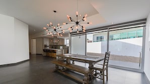 A spacious dining area with a long wooden table and benches, modern pendant lighting, and large sliding glass doors leading to a balcony. - Welcome to Your Perfect Beach Getaway F19, Welcome to Your Perfect Beach Getaway F19 (puerto penasco)