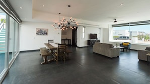 A spacious living area with a dining table, sofas, and a large window offering a city view. - Welcome to Your Perfect Beach Getaway F19, Welcome to Your Perfect Beach Getaway F19 (puerto penasco)