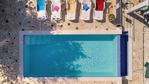 Ein rechteckiger Pool mit klarem, blauem Wasser, umgeben von einem mit Mosaikfliesen ausgelegten Deck.