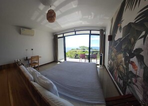 A bedroom with a large bed, a desk, and a view of the outdoors. - Entire Hotel (Montezuma)