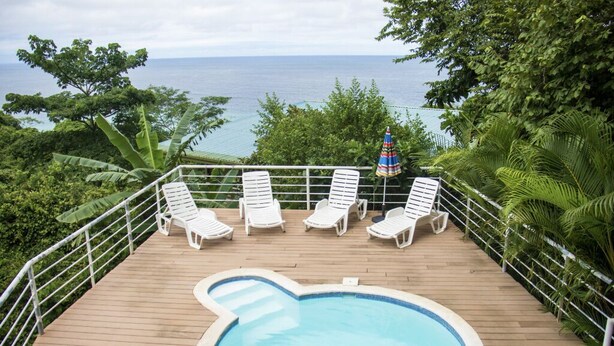 A pool area with white lounge chairs and a view of the ocean. - Entire Hotel (Montezuma)