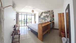 A bedroom with a bed, a wooden desk, a chair, a large window, and a mural. - Entire Hotel (Montezuma)
