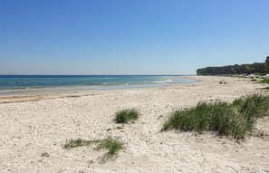 Enjoy a serene beach experience with calm waters and lush green surroundings.