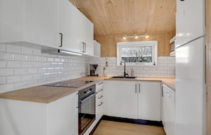 Enjoy cooking in this kitchen with an oven, white cabinetry, and a window above the sink offering a view of the outside.