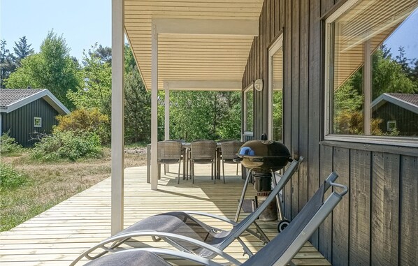 Relax and socialize in this outdoor patio area with lounge chairs, a table, and a barbecue grill.