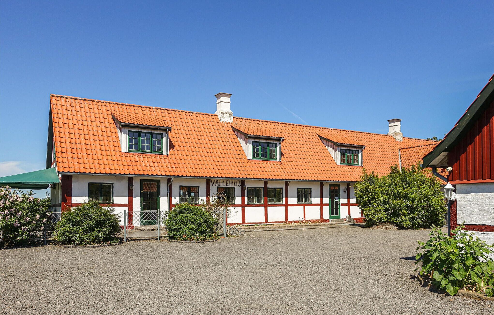 A traditional building with a red-tiled roof, white walls, and green window frames.