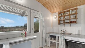 Een moderne keuken met een groot raam, houten plafond en inbouwplanken.