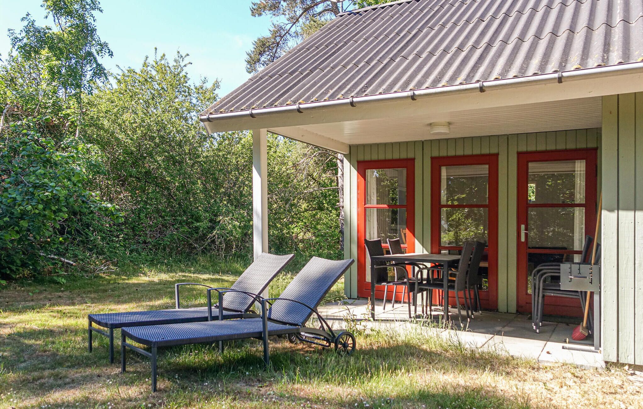 A small house with a porch, two lounge chairs, a table, and chairs.