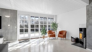 A spacious living room with a large window, a fireplace, and two leather chairs.