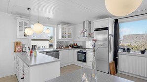 A modern kitchen with white cabinetry, a central island, stainless steel appliances, and pendant lighting.