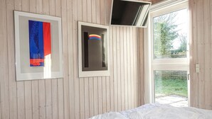 A bedroom with a wooden slat wall, a bed with white bedding, and two framed artworks. - 3 bedroom amazing home in Nexø (Nexø)