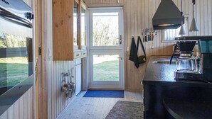 A kitchen with wooden walls, a large window, and a coffee machine. - 3 bedroom amazing home in Nexø (Nexø)
