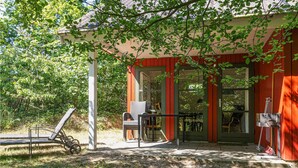 Un bâtiment rouge avec un porche abrité, un vélo et du mobilier d’extérieur.