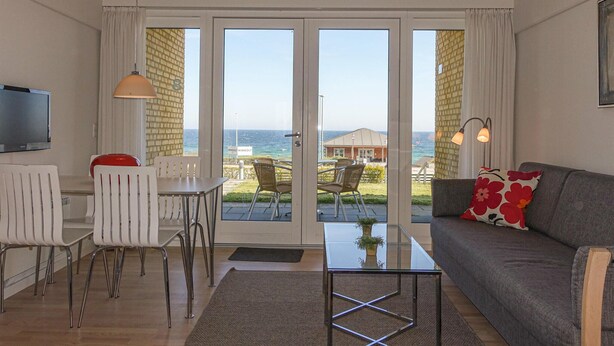 Un soggiorno moderno con una porta vetrata che si apre su un balcone con vista sul mare.