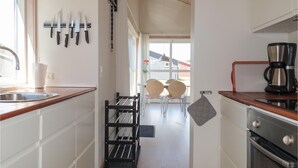 A modern kitchen with a sink, stove, and coffee maker. There are two chairs and a table in the background. - Stunning home in Gudhjem with WiFi (Gudhjem)