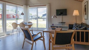 A modern living room with a dining area, large windows, a flat-screen TV, and a sofa. - Stunning home in Gudhjem with WiFi (Gudhjem)