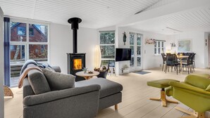 Ein modernes Wohnzimmer mit Kamin, großen Fenstern und einem Essbereich.