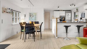 Eine moderne Küche mit Essbereich, mit Holzboden, weißen Schränken und zeitgemäßen Barhocker.