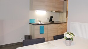 Una cucina compatta con mobili in legno, un lavandino, una macchina del caffè e un piccolo cestino.