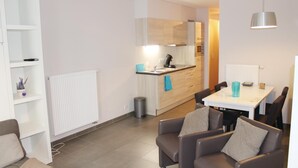 Una cucina moderna con isola centrale, zona pranzo con tavolo e sedie e un’area salotto con divani.