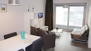 Un soggiorno moderno con un divano, un tavolo da pranzo e una TV a parete.