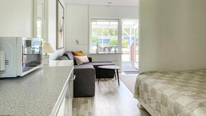 A compact room with a sofa, a small table, a bed, and a kitchenette area. - Amazing apartment in Nexø with sauna (Nexø)