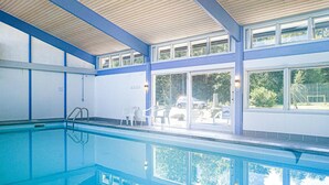 A swimming pool with clear blue water, surrounded by a covered area with large windows and doors. - Amazing apartment in Nexø with sauna (Nexø)