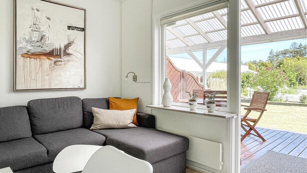 A modern living room with a grey sofa, a white chair, and a wooden table with potted plants. - Amazing apartment in Nexø with sauna (Nexø)