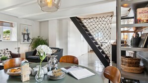 Un salon moderne avec un coin repas, comprenant une table ronde, des chaises, une table basse et une bibliothèque.