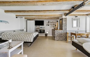 A compact, modern bedroom with a bed, bedside table, and a small kitchenette area.